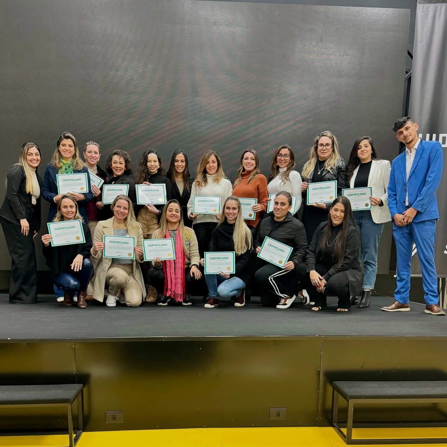 Turma formada no palco do evento segurando os certificados