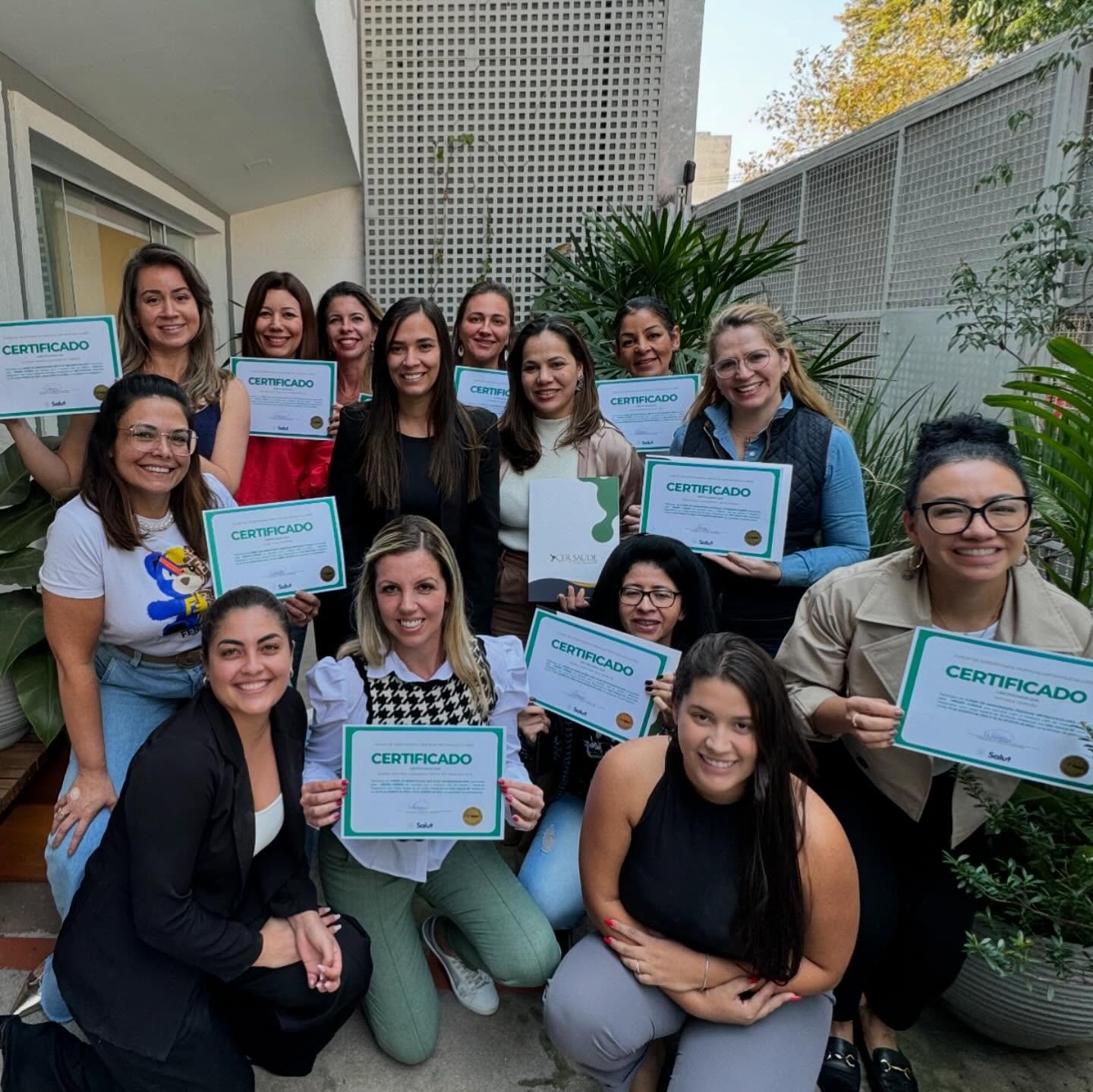 Turma formada ao ar livre segurando os certificados Salut
