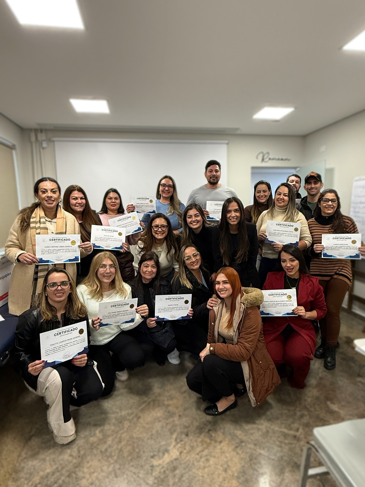 Turma de formação em sala segurando os certificados